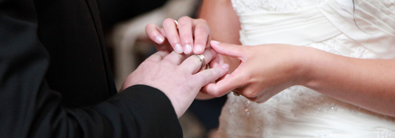 Die Braut steckt ihrem Mann bei der Hochzeit den Ring an den Finger