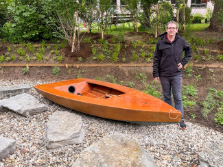 Pfarrer Michael Rummel steht neben einem kleinen Boot